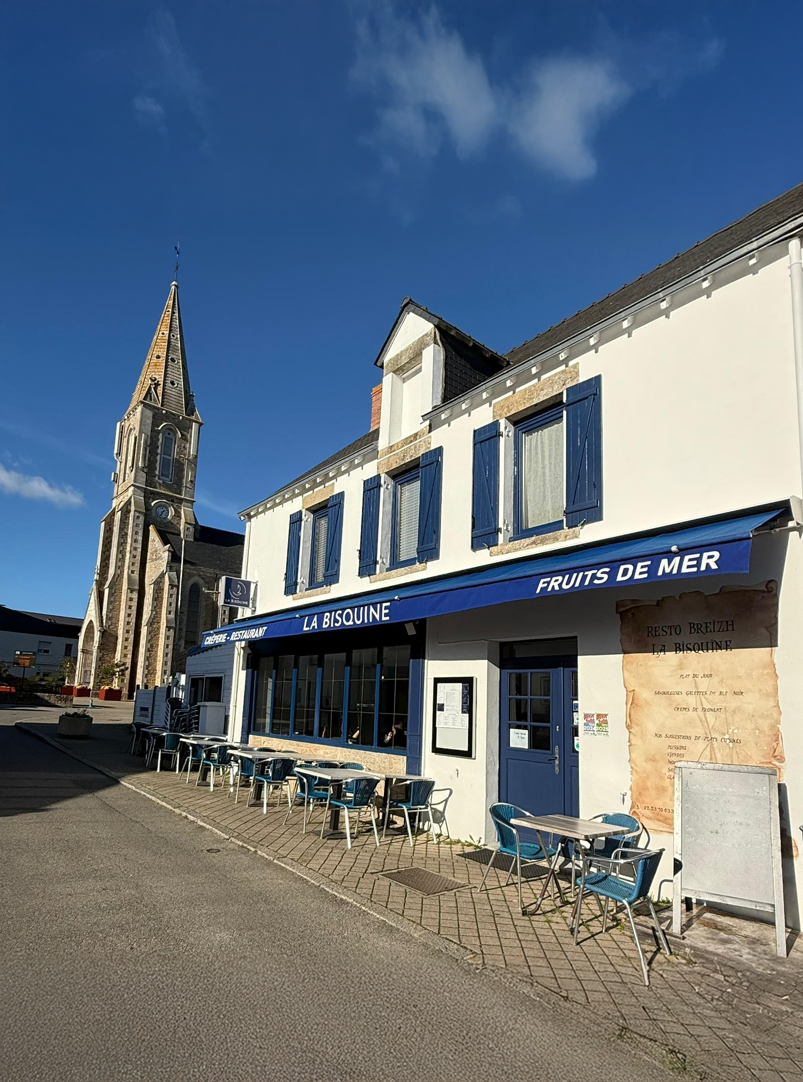 Façade du restaurant La Bisquine à Pénestin avec terrasse et église en arrière-plan